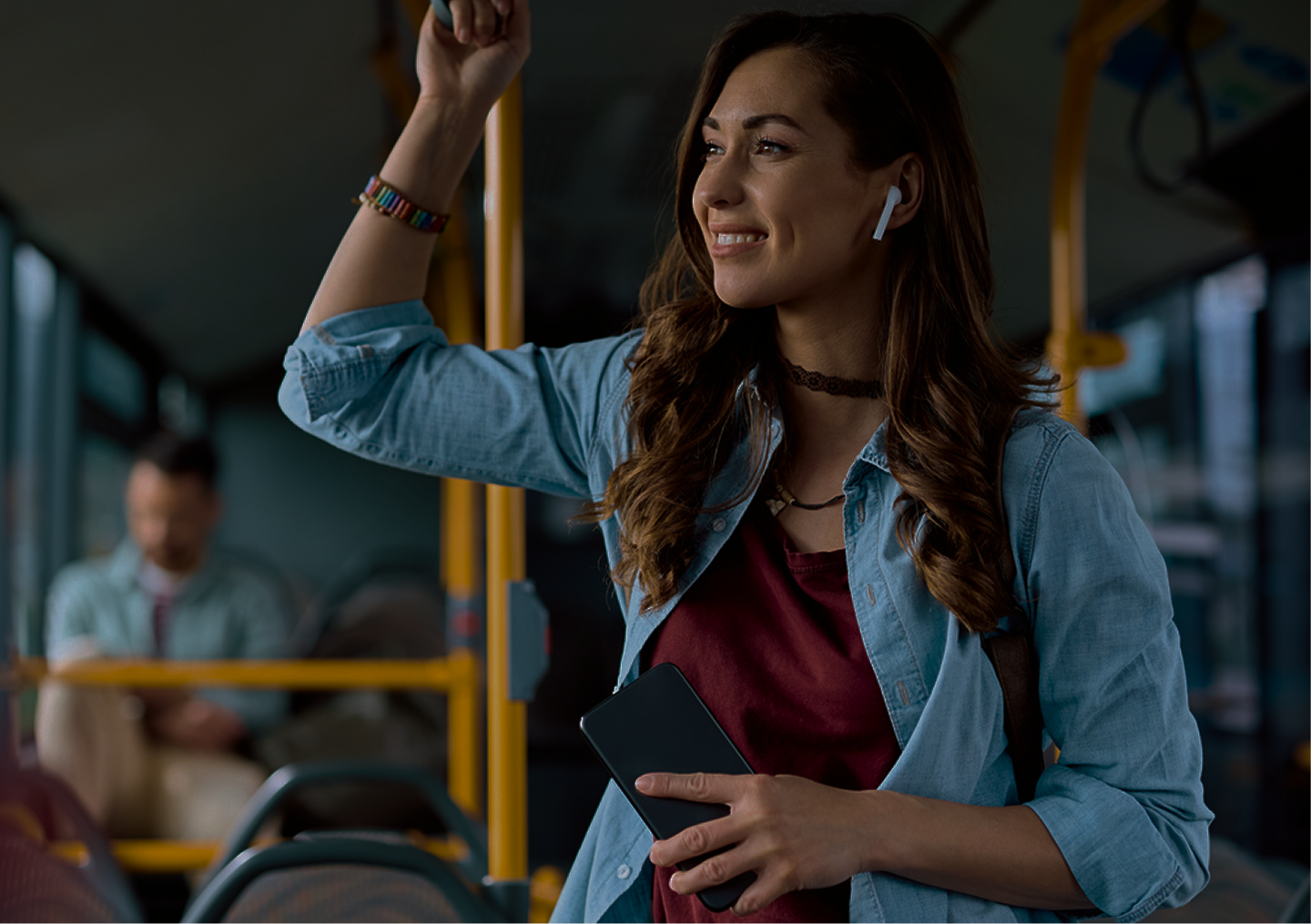 Woman standing on bus with earbuds in.