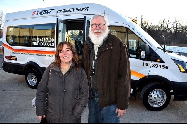 Two riders pose in front of a NOTA/SMART Community Transit cutaway